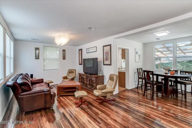 a living room with furniture a dining table and a floor to ceiling window
