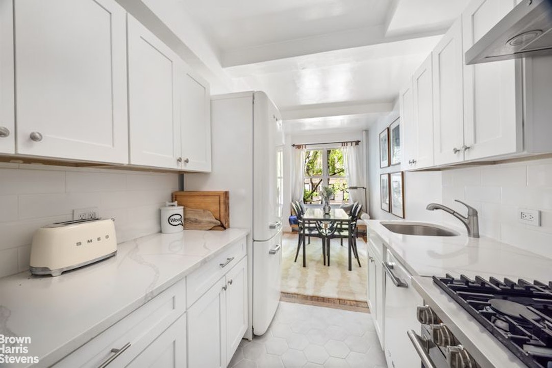 12 East 97th Street, Unit 2G Manhattan, NY 10128 - Photo 3 of 7 a kitchen with granite countertop a sink a stove and cabinets
