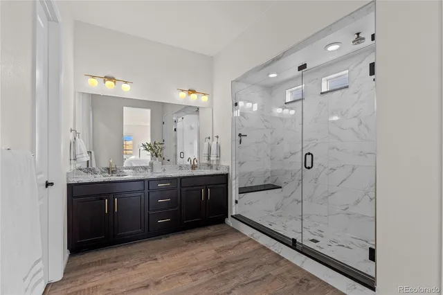 a bathroom with a granite countertop sink a mirror and shower