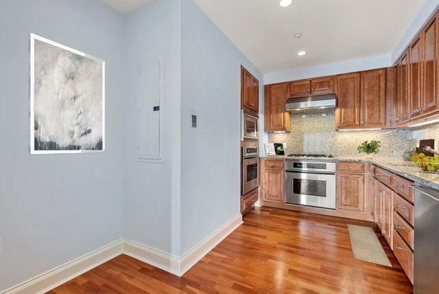 a kitchen with granite countertop a refrigerator and wooden floor