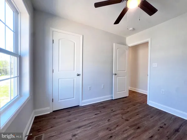 an empty room with wooden floor cabinet and windows