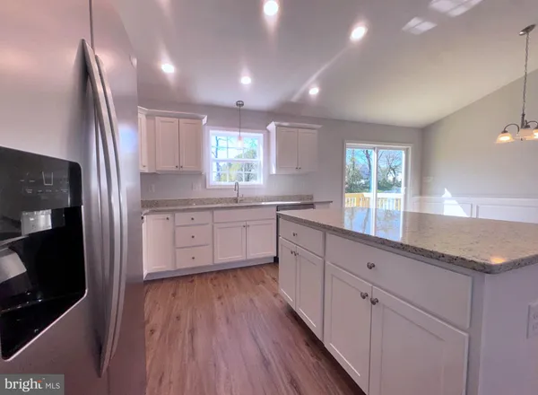 a kitchen with white cabinets with wooden floor and window