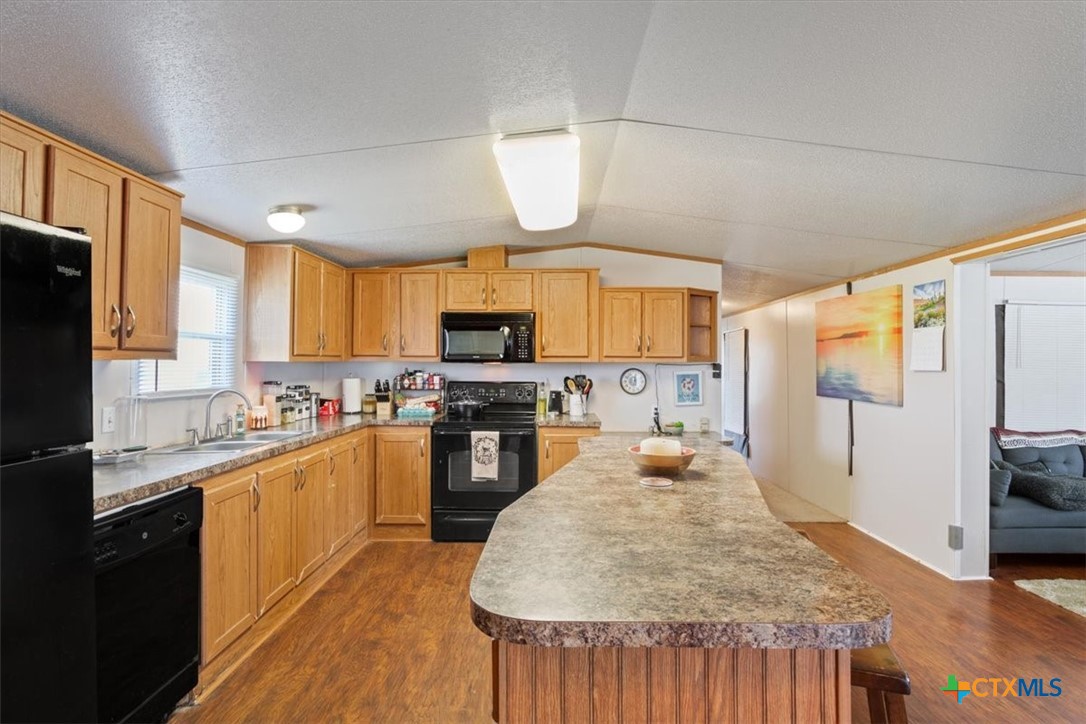 216 Moore Street Rogers, TX 76569 - Photo 8 of 29 a large kitchen with kitchen island a large counter top space a sink stainless steel appliances and cabinets