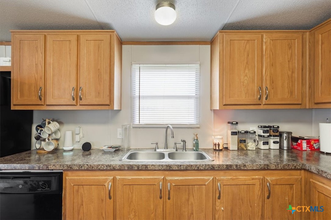 216 Moore Street Rogers, TX 76569 - Photo 10 of 29 a kitchen with granite countertop stainless steel appliances white cabinets sink and window