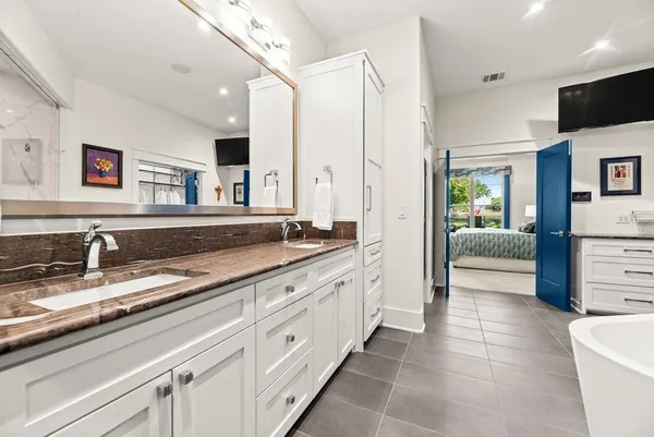 a spacious en suite bathroom with a granite countertop sink mirror and bathtub