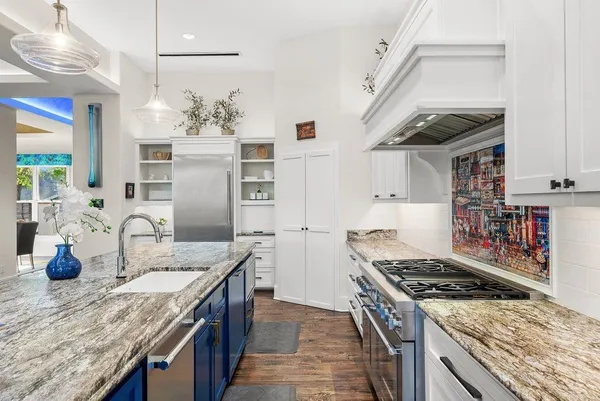 a kitchen with stainless steel appliances granite countertop a stove a refrigerator a sink dishwasher and wooden cabinets with wooden floor