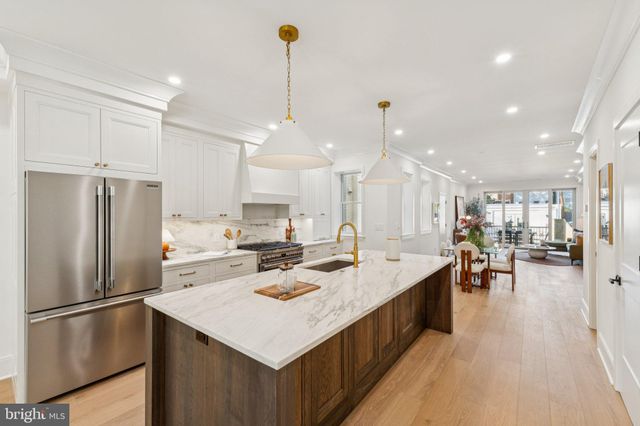 a kitchen with a stove a sink a center island and wooden floor