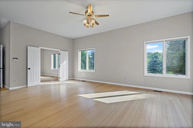a view of an empty room with wooden floor and a window