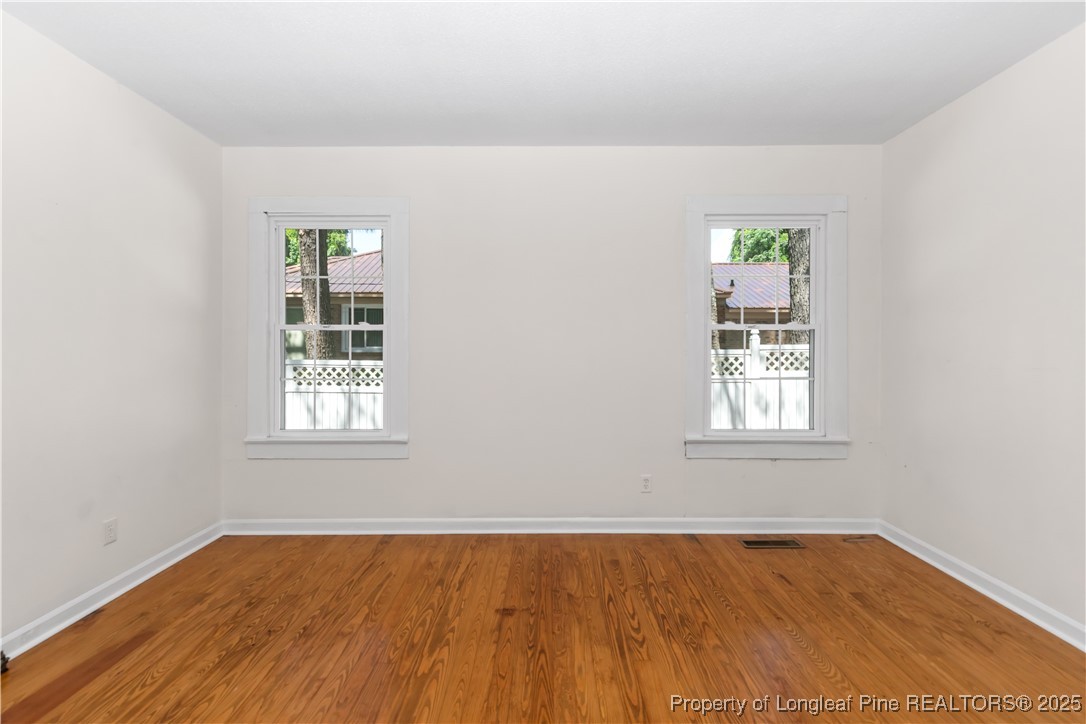 726 West M Street Erwin, NC 28339 - Photo 9 of 24 an empty room with wooden floor and windows