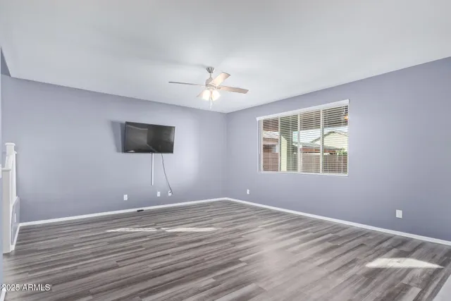 a view of an empty room with window and wooden floor