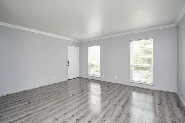 an empty room with wooden floor and windows