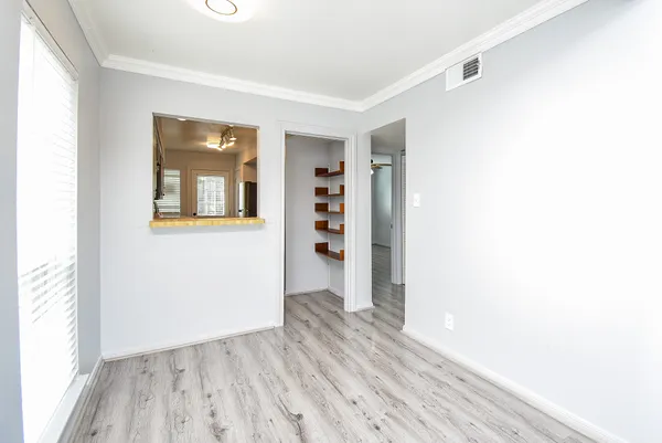 a view of an empty room with wooden floor and a window