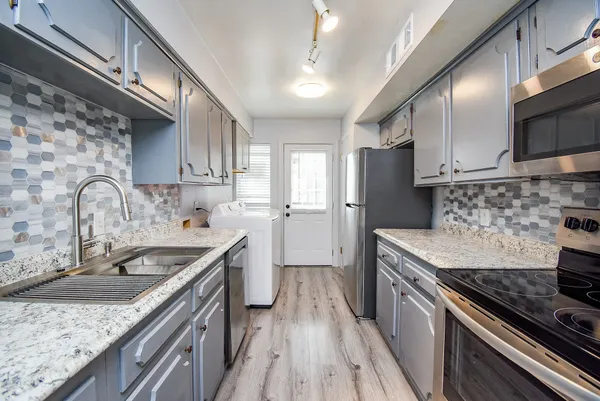 a kitchen with stainless steel appliances granite countertop a sink stove and refrigerator