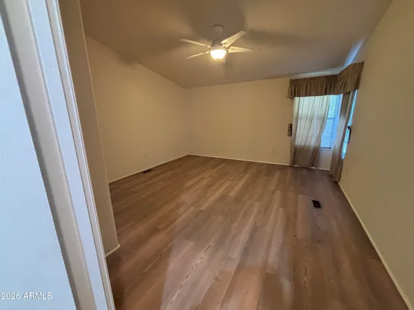 en empty room with wooden floor and fan