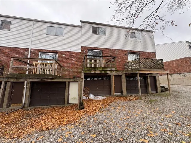 a front view of a house with a large tree