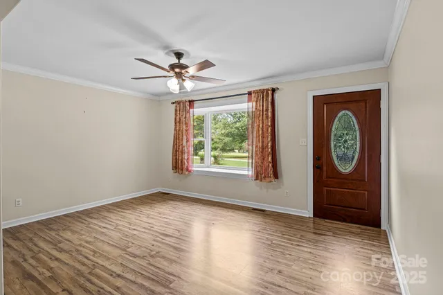 a view of an empty room with window and wooden floor