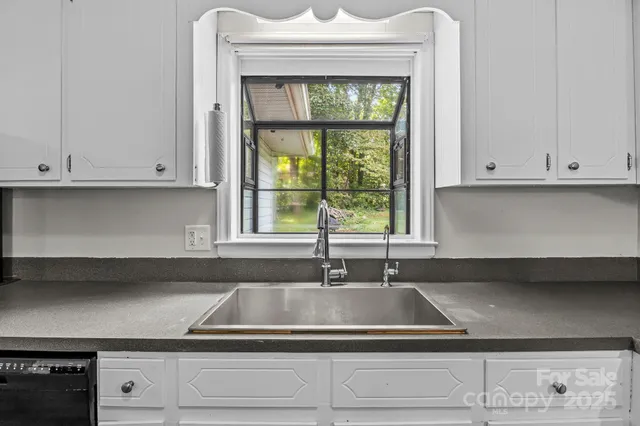 a kitchen with granite countertop white cabinets and window