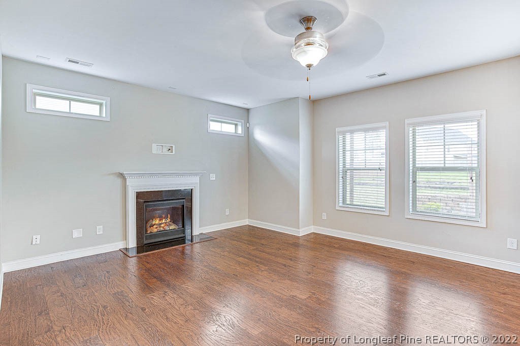 268 Turriff Way Cameron, NC 28326 - Photo 9 of 44 an empty room with windows a fireplace and wooden floor