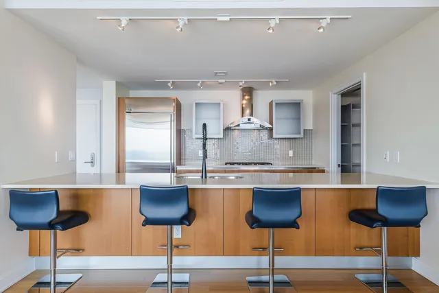 a kitchen with stainless steel appliances granite countertop a counter space and chairs in it