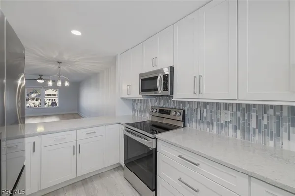 a kitchen with white cabinets and appliances
