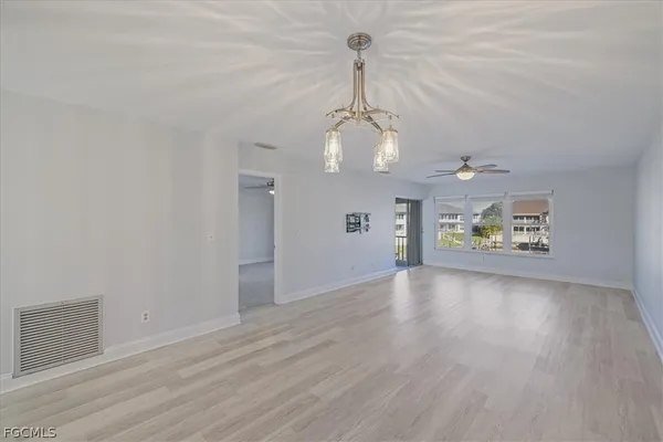 a view of an empty room with wooden floor and windows