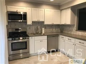 a kitchen with stainless steel appliances white cabinets and a stove top oven