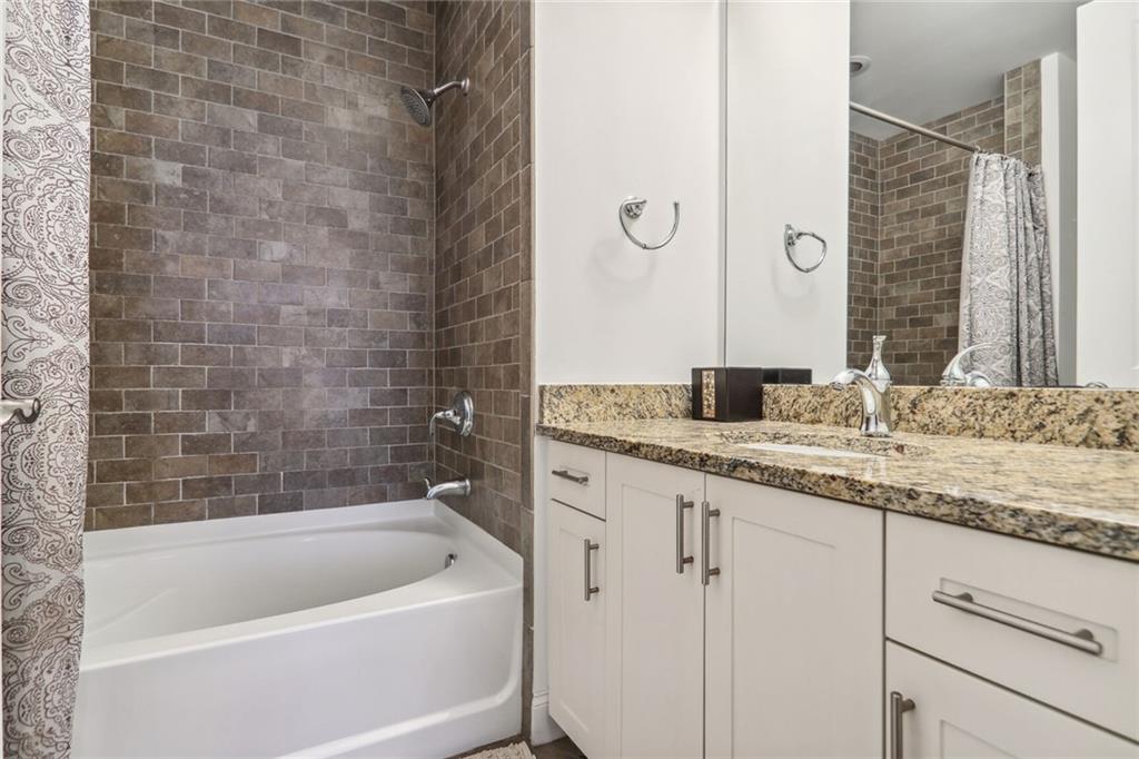270 17th Street Northwest Atlanta, GA 30363 - Photo 11 of 15 a bathroom with a granite countertop sink a mirror and a bathtub