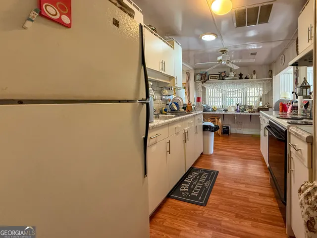 a kitchen with stainless steel appliances a refrigerator a sink dishwasher a stove top oven a dining table and chairs with wooden floor