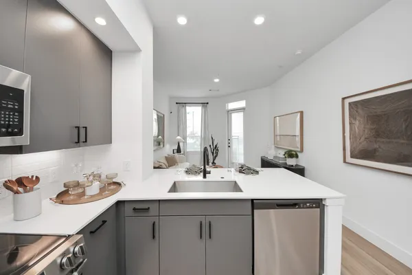 a living room with stainless steel appliances furniture and a kitchen view