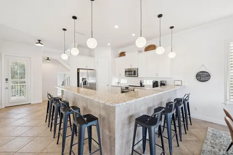 a kitchen with stainless steel appliances kitchen island granite countertop a table chairs and a view of living room