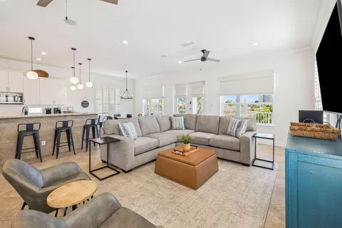 a living room with furniture a flat screen tv and kitchen view