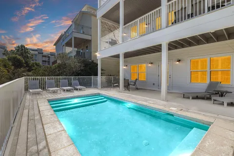a view of swimming pool with lawn chairs and plants