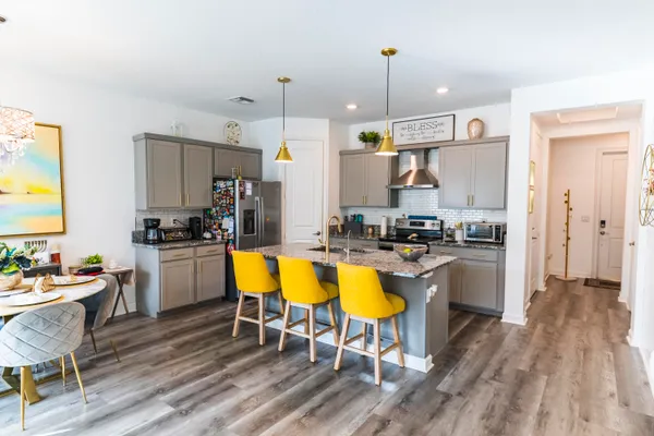 a kitchen with a dining table chairs sink and wooden floor