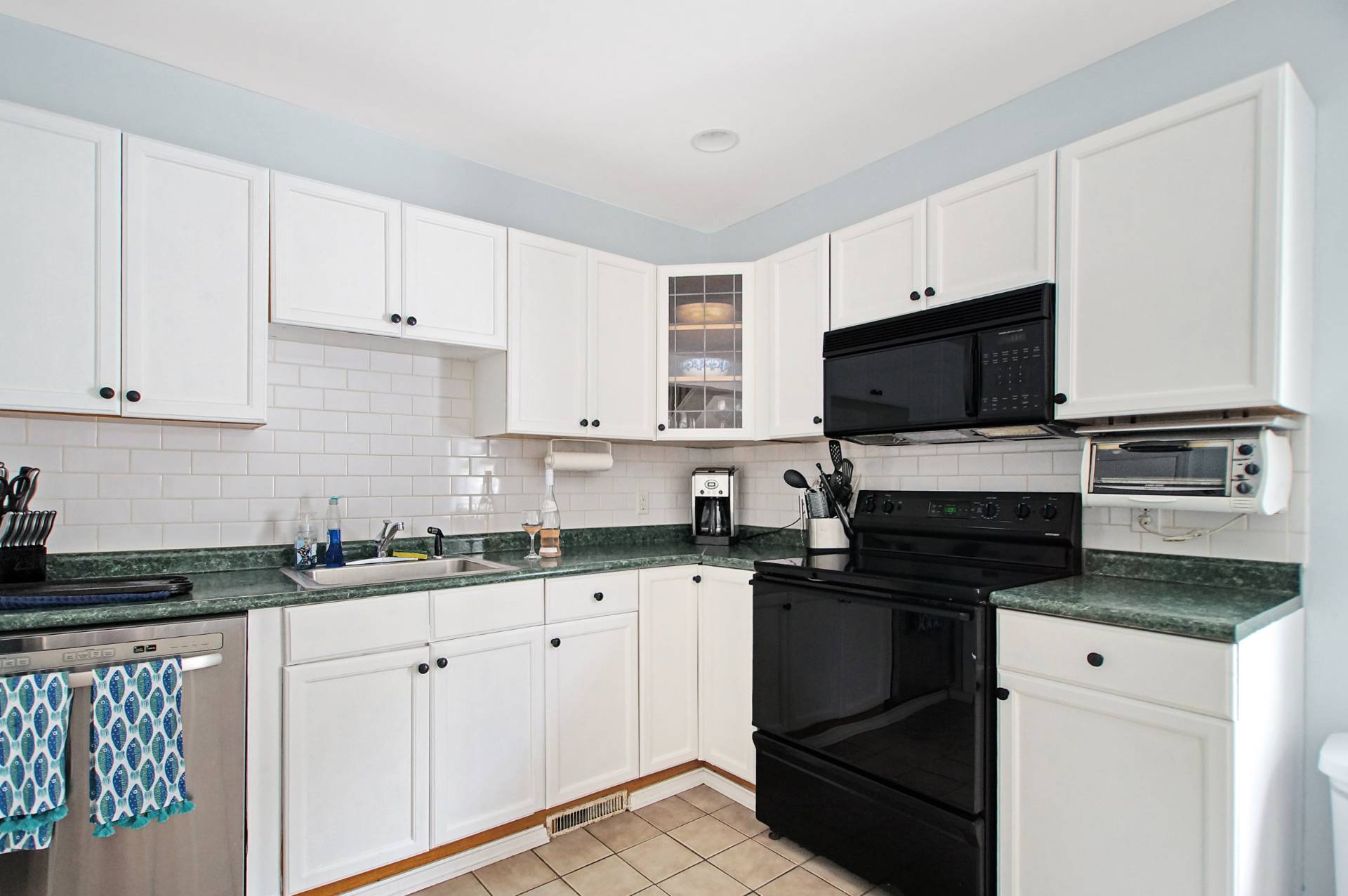 16 Norbury Road Hampton Bays, NY 11946 - Photo 5 of 32 a kitchen with granite countertop white cabinets and black appliances