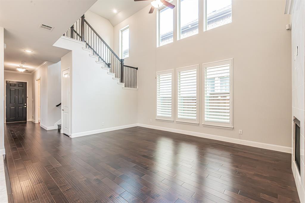 304 Adam Way Euless, TX 76040 - Photo 12 of 39 Unfurnished living room with plenty of natural light, dark wood-style floors, a ceiling fan, a high ceiling, and a fireplace