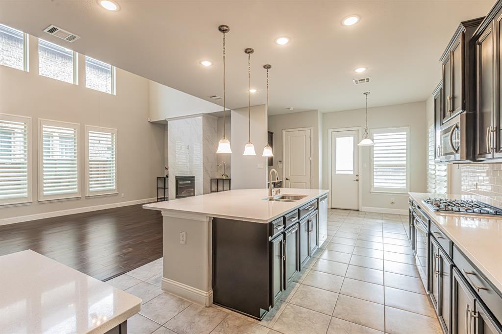 304 Adam Way Euless, TX 76040 - Photo 39 of 39 Kitchen featuring open floor plan, decorative backsplash, light tile patterned floors, a kitchen island with sink, and pendant lighting