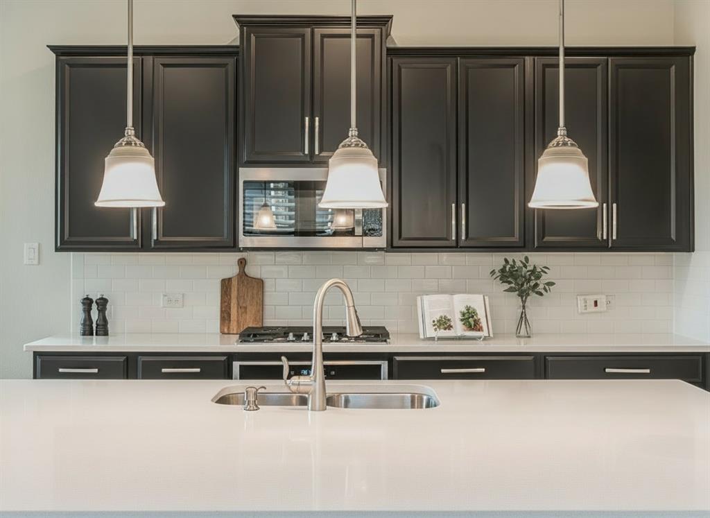 304 Adam Way Euless, TX 76040 - Photo 14 of 39 Kitchen featuring pendant lighting, stainless steel microwave, light stone countertops, and backsplash