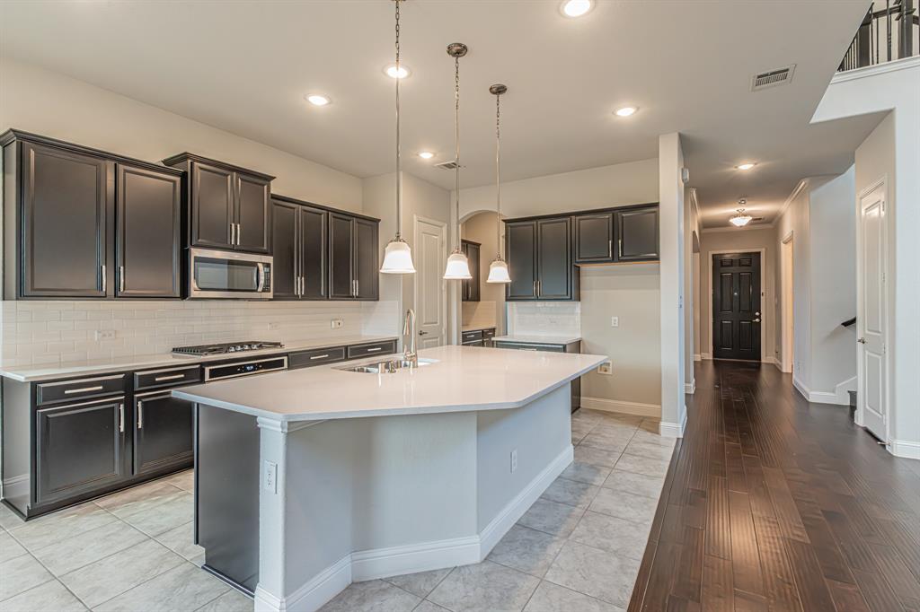 304 Adam Way Euless, TX 76040 - Photo 15 of 39 Kitchen featuring backsplash, a large island, stainless steel appliances, pendant lighting, and light tile patterned flooring