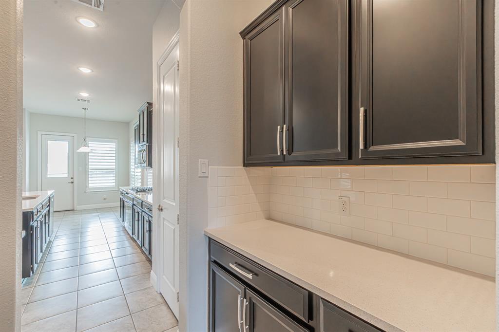 304 Adam Way Euless, TX 76040 - Photo 16 of 39 Kitchen with decorative backsplash, light stone counters, light tile patterned flooring, and decorative light fixtures