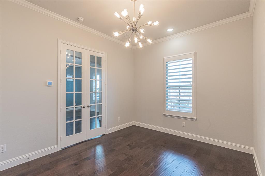 304 Adam Way Euless, TX 76040 - Photo 6 of 39 Empty room with french doors, a chandelier, dark wood-style floors, and ornamental molding