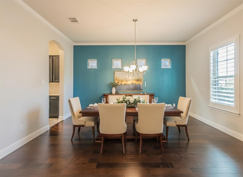 304 Adam Way Euless, TX 76040 - Photo 7 of 39 Dining room with arched walkways, dark wood-type flooring, suspended lighting, and crown molding
