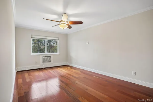 an empty room with wooden floor ceiling fan and windows