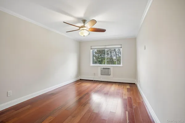 an empty room with wooden floor fan and windows