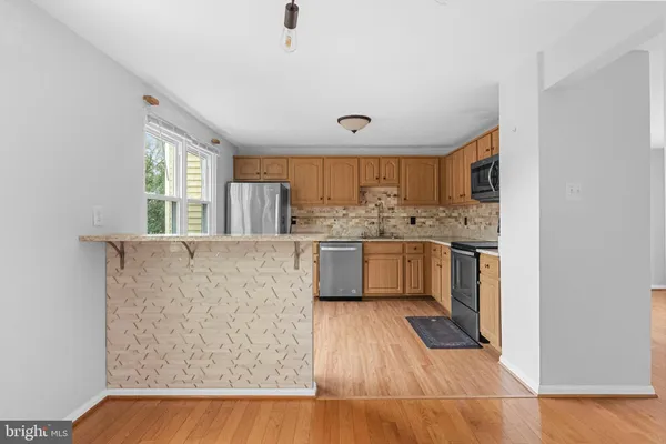 a kitchen with stainless steel appliances a sink a stove a refrigerator cabinets and a window