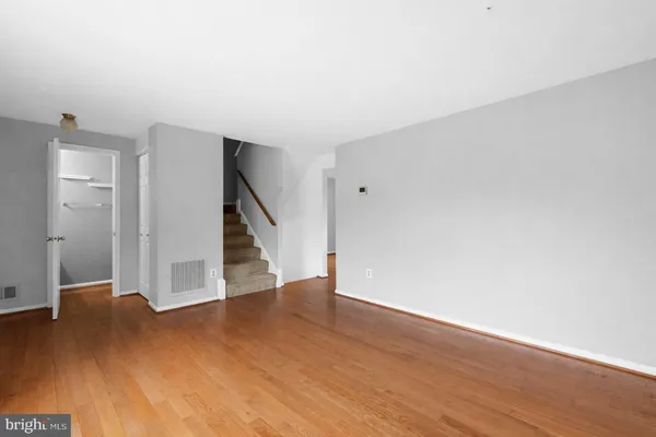 a view of an empty room with wooden floor and stairs