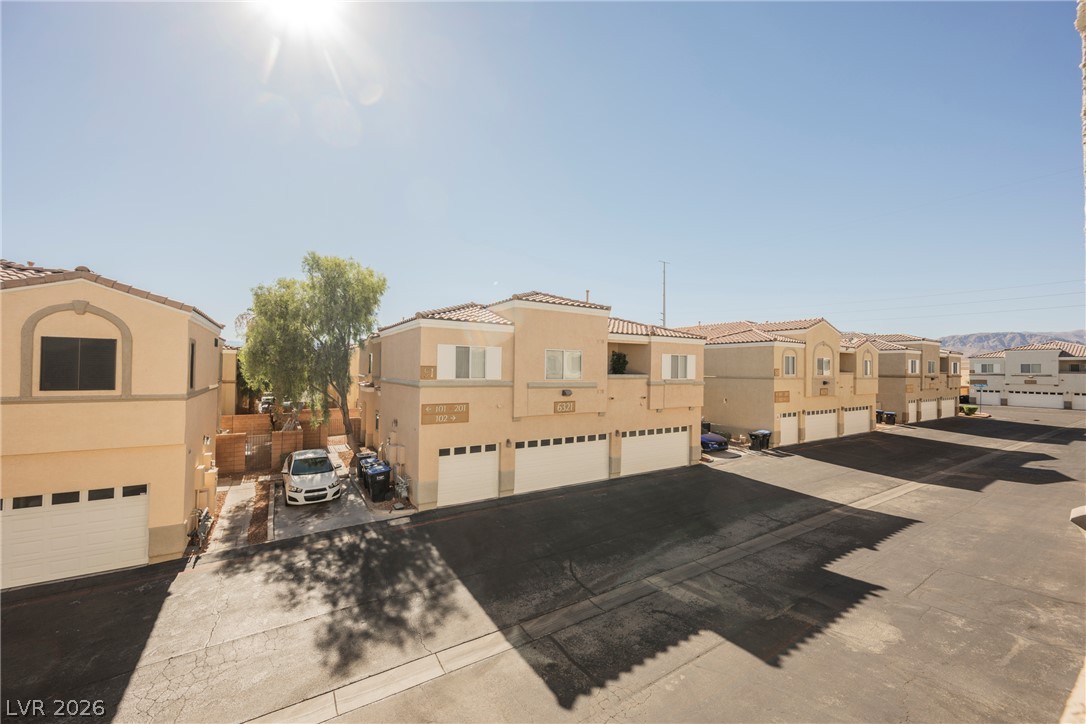 6320 Snap Ridge Street, Unit 201 North Las Vegas, NV 89081 - Photo 52 of 56 Rows of beige townhouses with individual garages under a clear, bright sky.