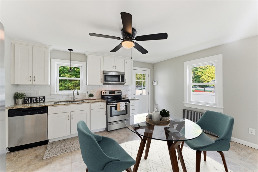 45 Meadow Street Ludlow, MA 01056 - Photo 4 of 32 a kitchen with stainless steel appliances granite countertop a stove a sink a dining table and chairs with wooden floor