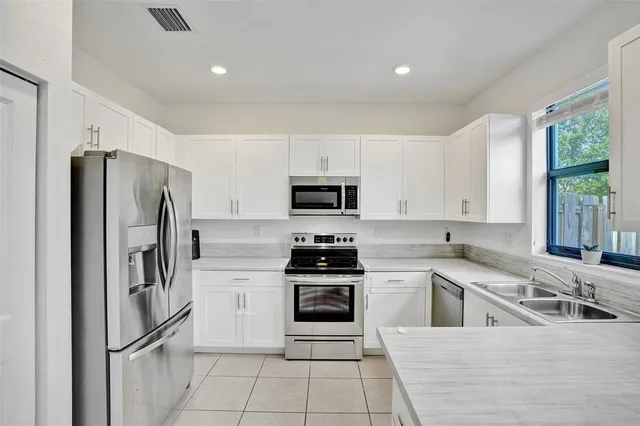 a kitchen with white cabinets and stainless steel appliances