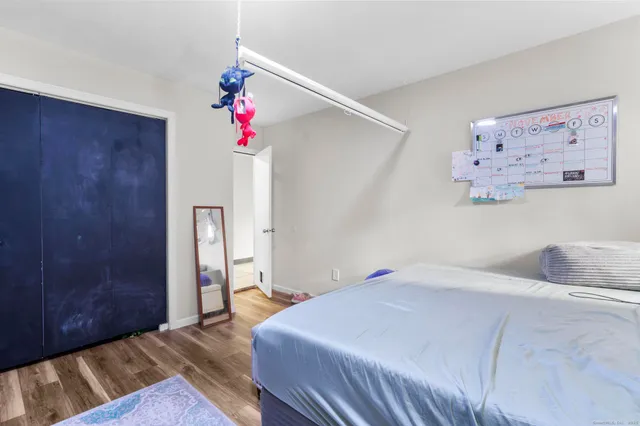 a bedroom with a bed a dresser and a painting on the wall