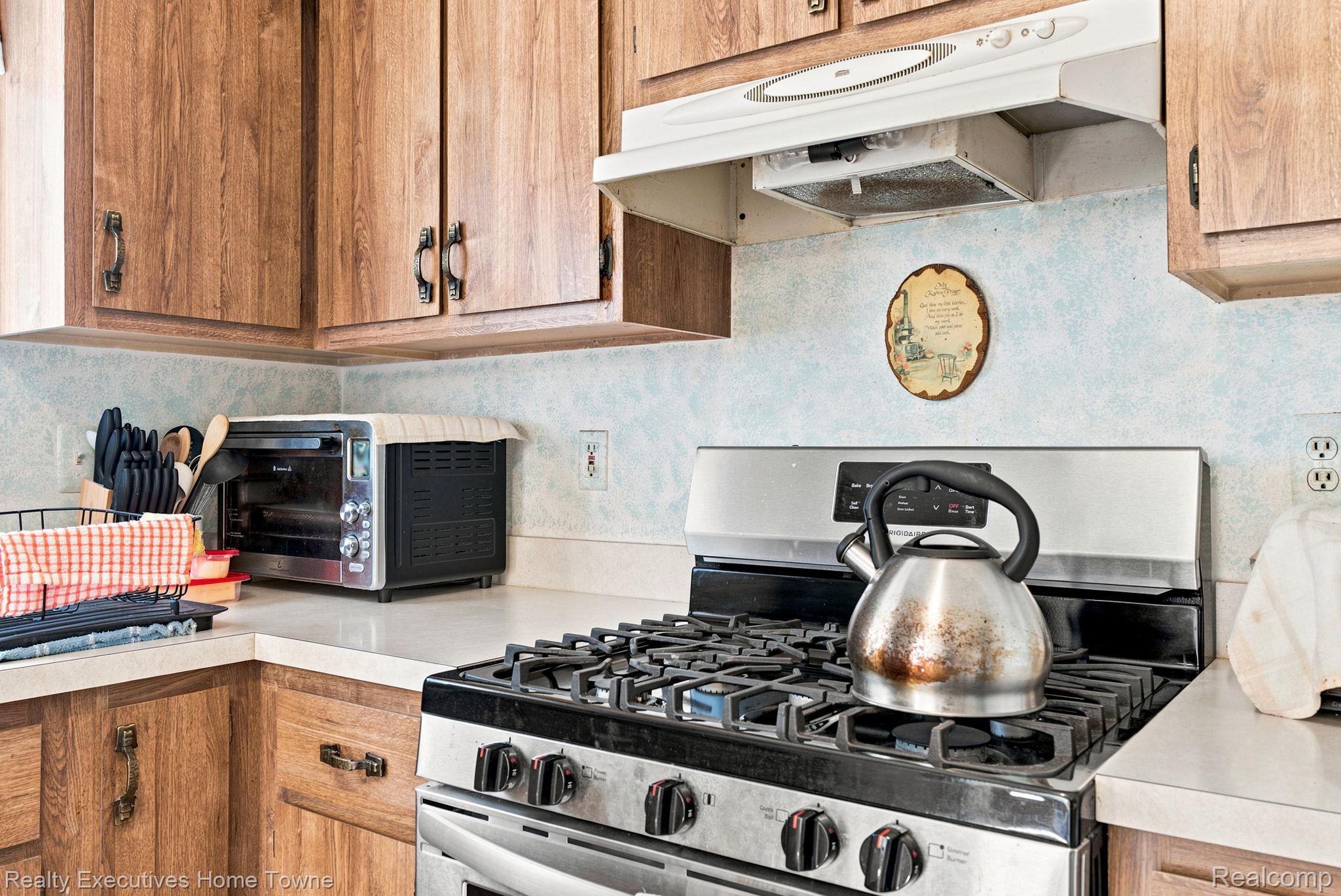959 Braidwood Road Memphis, MI 48041 - Photo 24 of 58 Kitchen featuring wood-finish cabinetry, light countertops, and a stainless steel gas range with overhead ventilation
